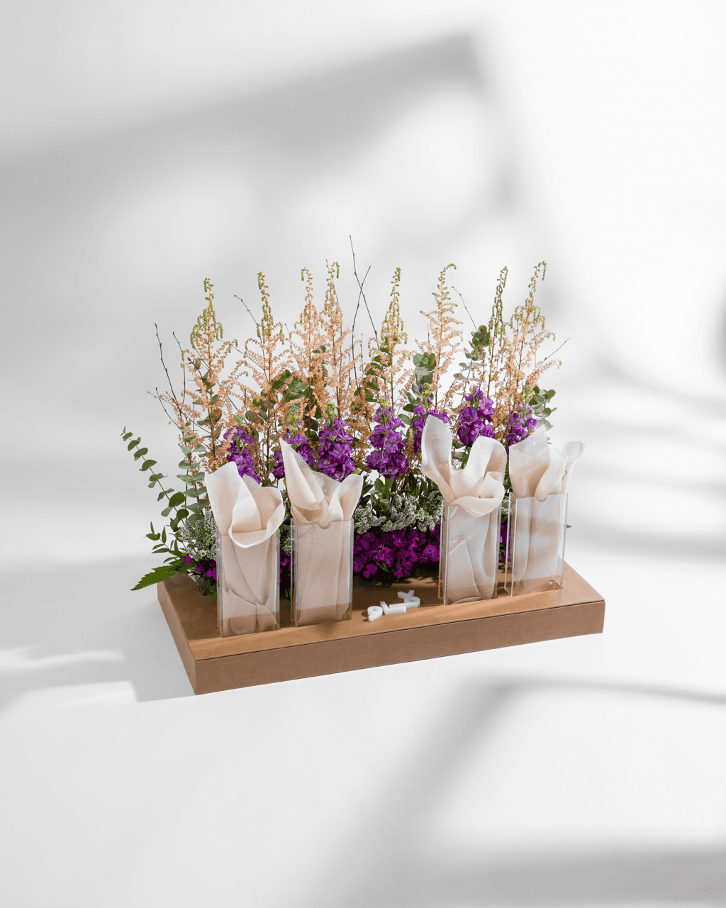 Purple and white flowers in glass vases on a wooden Vow platform
