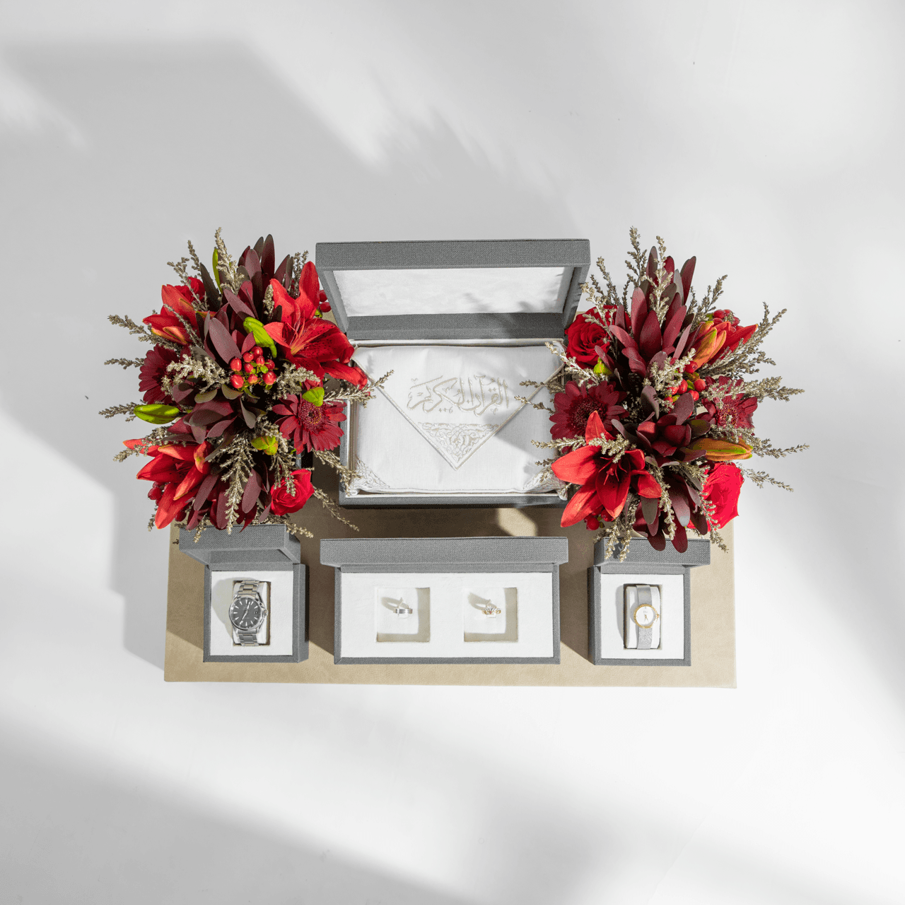 Full ceremonial Vow arrangement with Quran, watches, and red florals on grey platform