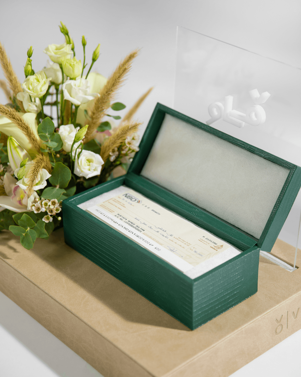 Green leather Vow box open to reveal bank cheque with white roses arrangement