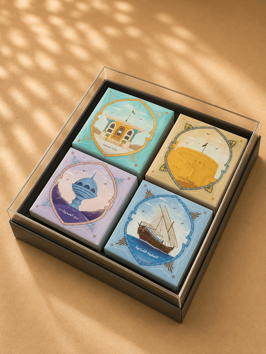 Four hand-illustrated Omani landmark gift boxes in a glass tray