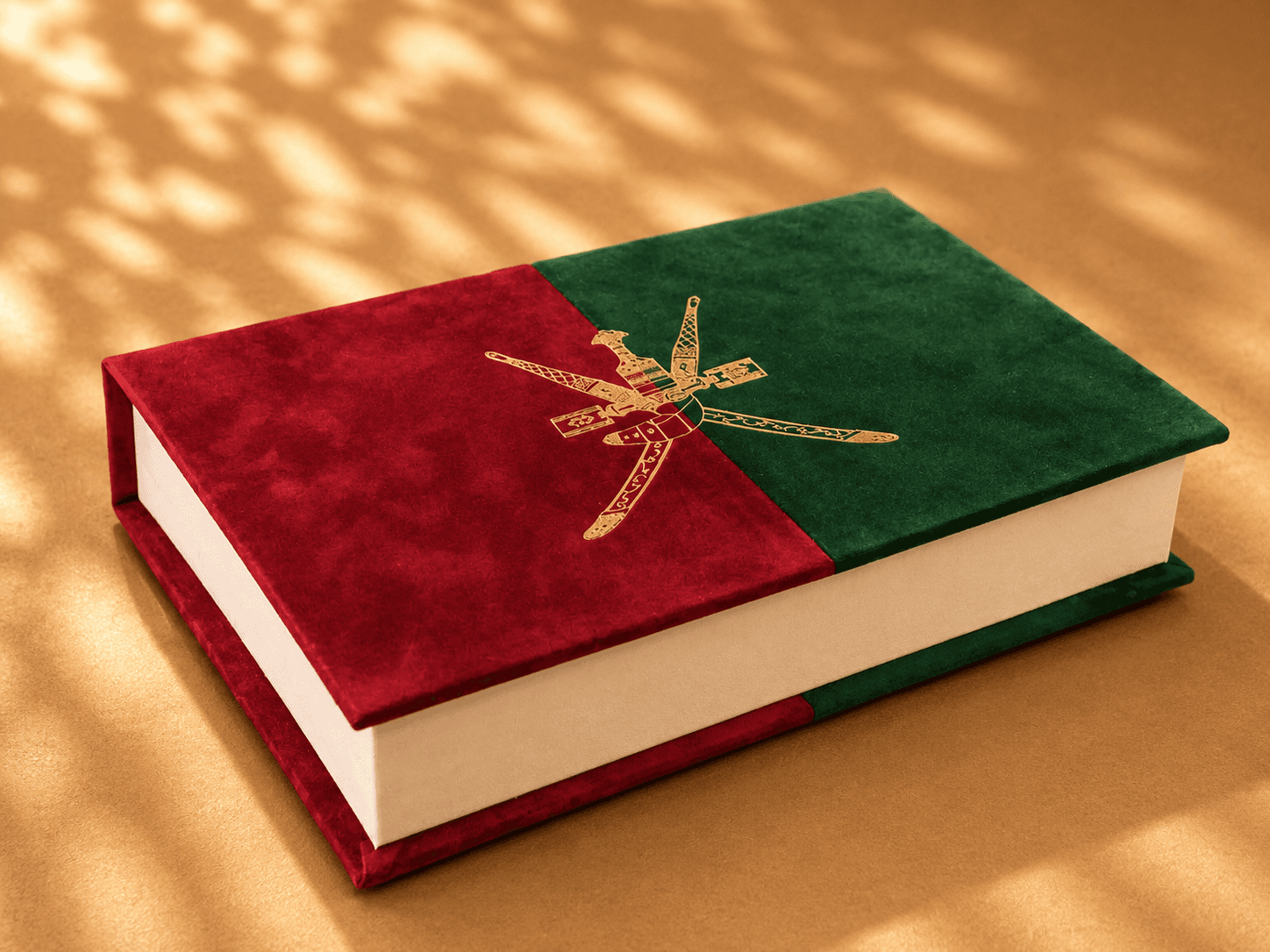 Red and green Omani emblem suede book on gold surface