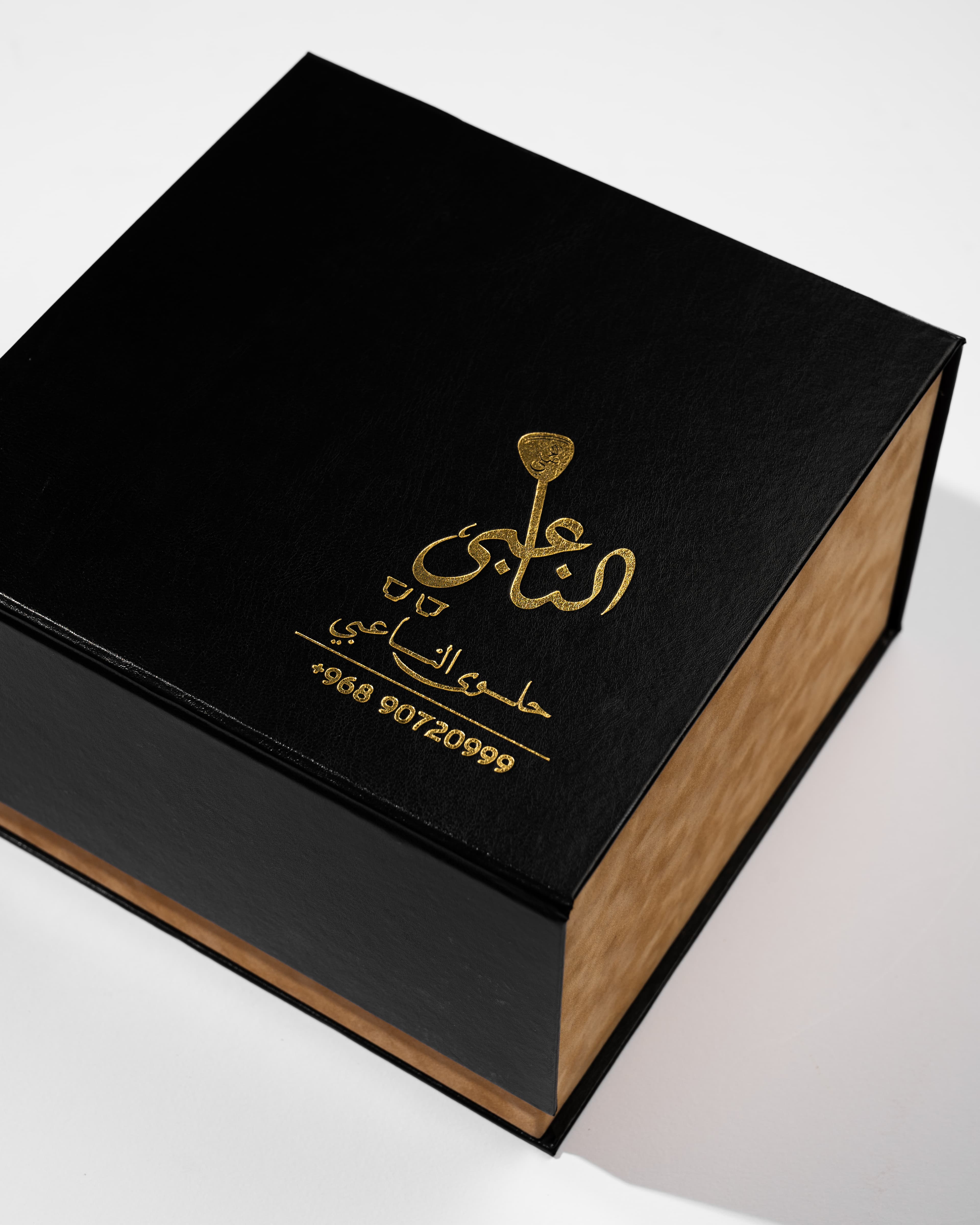 Black and wood luxury gift box with gold Arabic calligraphy branding